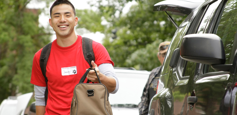 Student smiling with a name sticker saying "Jeremy" holding a canvas bag.