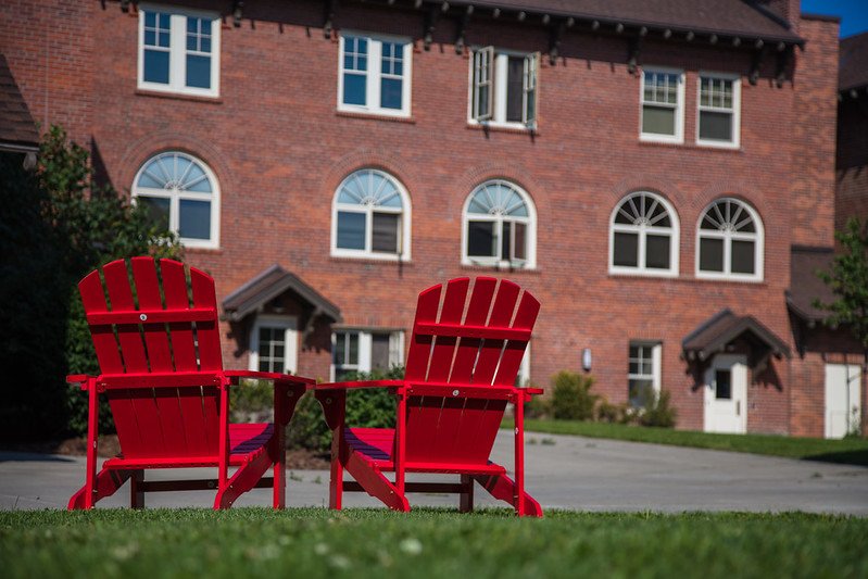 Two red adirondack chairs on the lawn outside of a CWU residence hall.