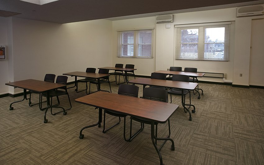 Inside of the Elaine Wright Room, set up classroom-style with six tables facing the front of the room, and two chairs at each table.