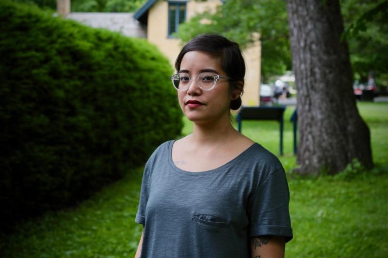 Photo of Danni Quintos wearing glasses with a hedge and tree behind her