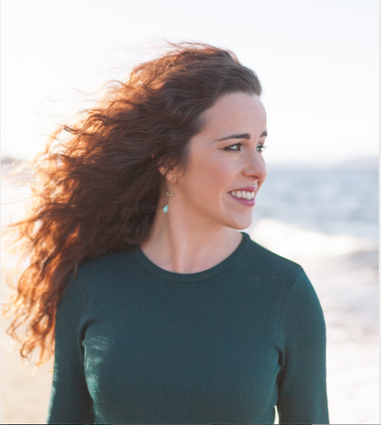 Portrait of Kristen Millares-Young wearing a green long-sleeve top and looking off to the side with a smile.