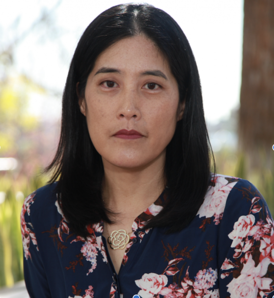 Portrait of Victoria Chang staring into the camera and wearing a floral blouse