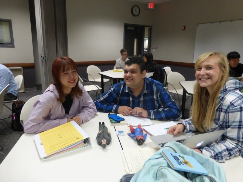 Three students sitting at a table, smiling.