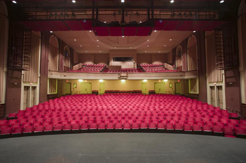 An image of the audience seating for Mcconnell Auditorium. There are two levels of seats and the seats are red.