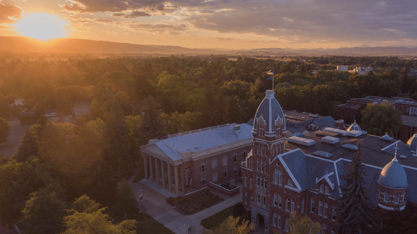 Aerial shot of Barge hall, cloudy skies, sun setting behind mountains in the distance