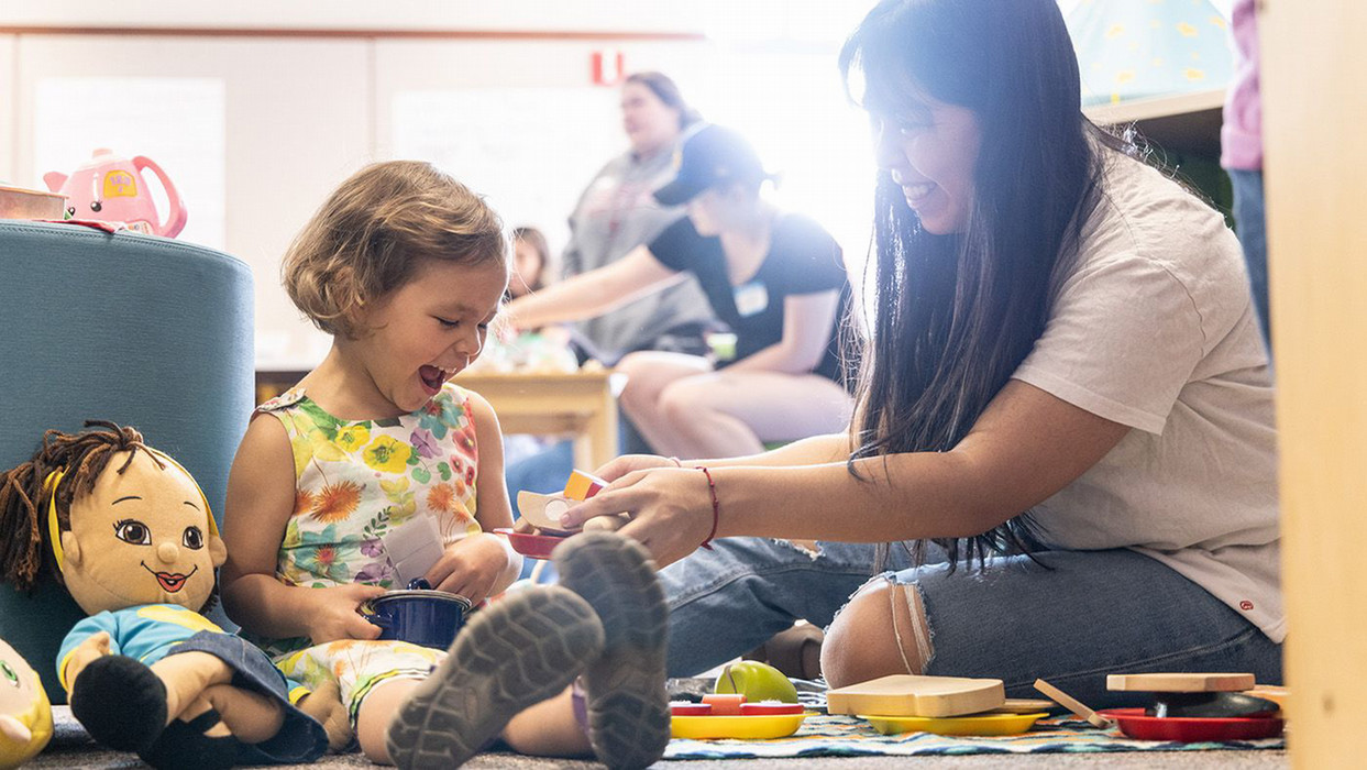 A woman apart of the family resource center within Central Washington University shares a laugh with a little girl.