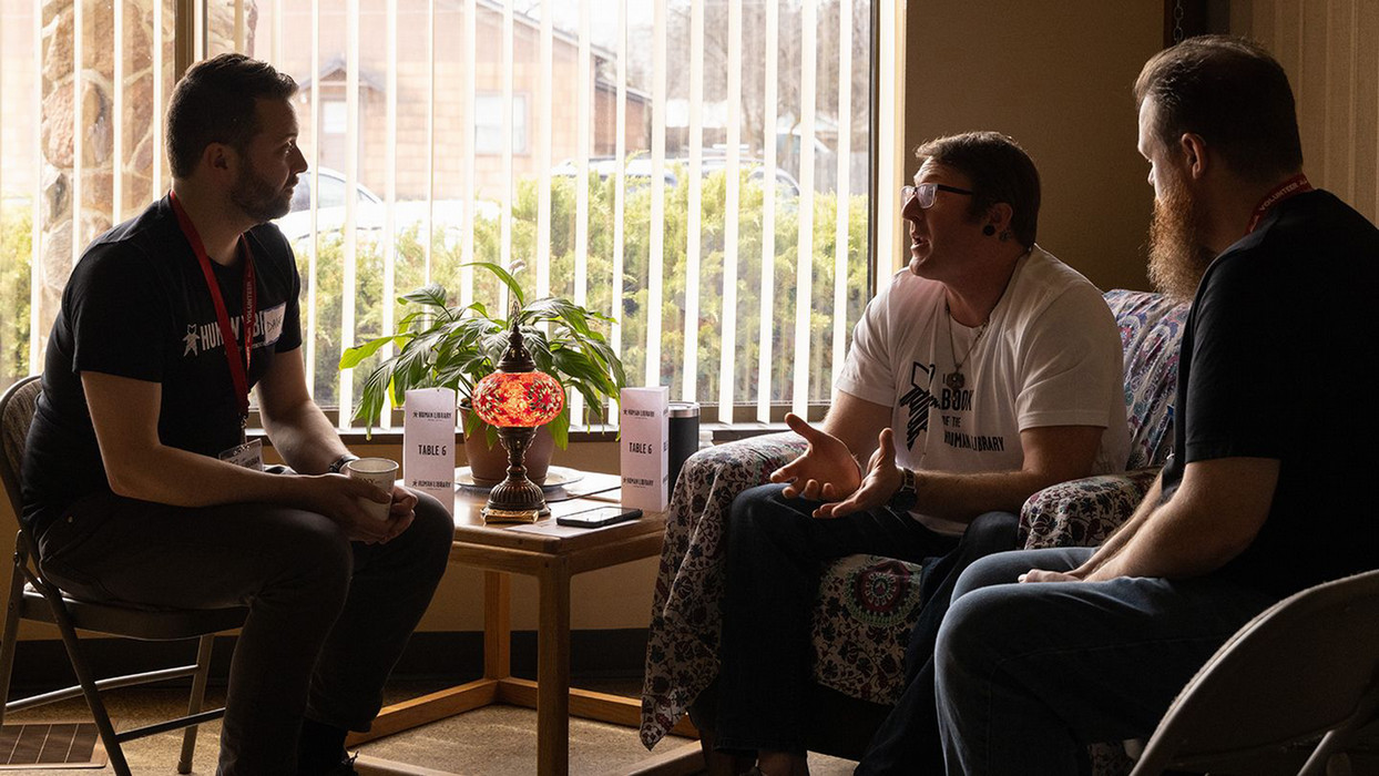 Three men sit in a room within the philosophy department at Central Washington University engage in conversation.