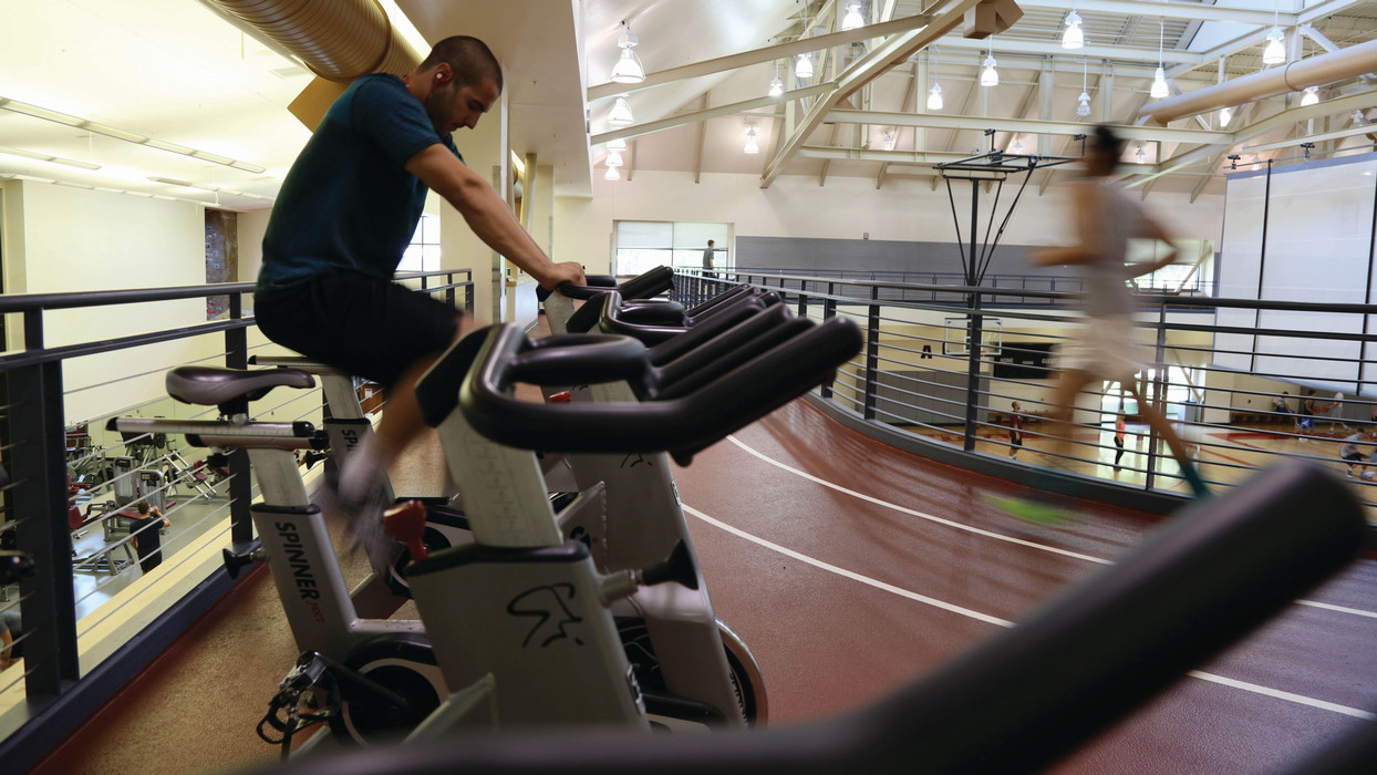 A man within the recreation center cycles as cardio.