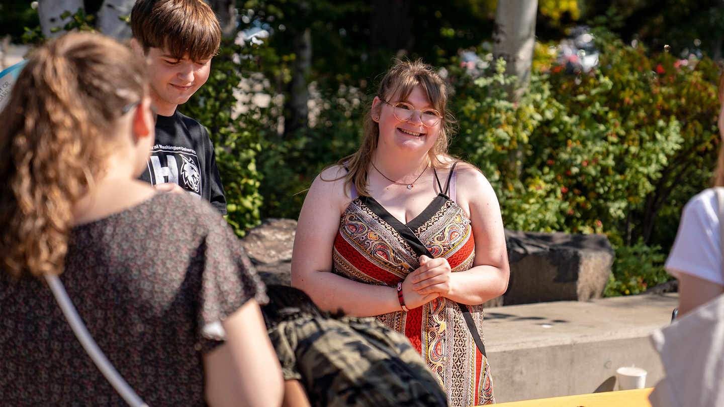 The image focuses on a girl smiling outside, she is with friends.