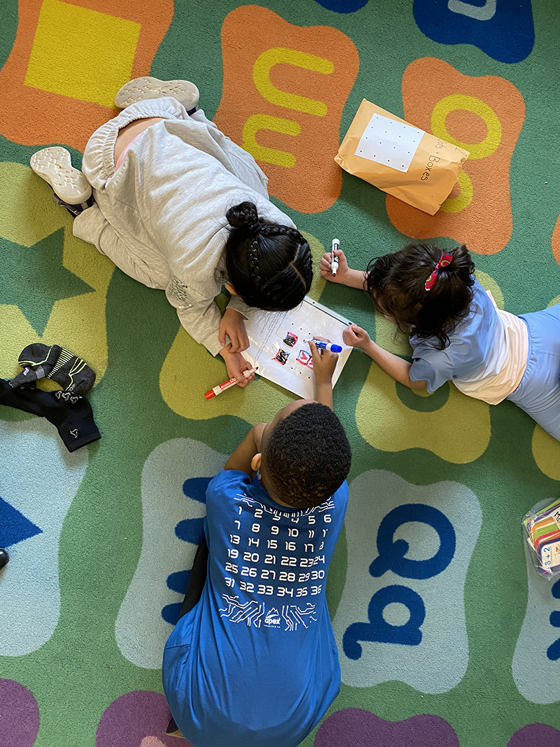 Elementary students work together on a colorful floor mat