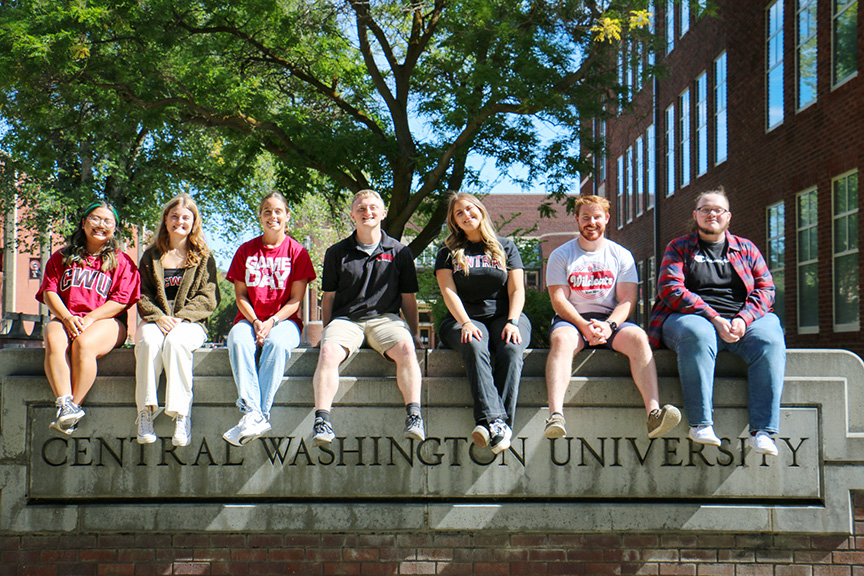 CAT Center student workers sit on a concrete wall at CWU