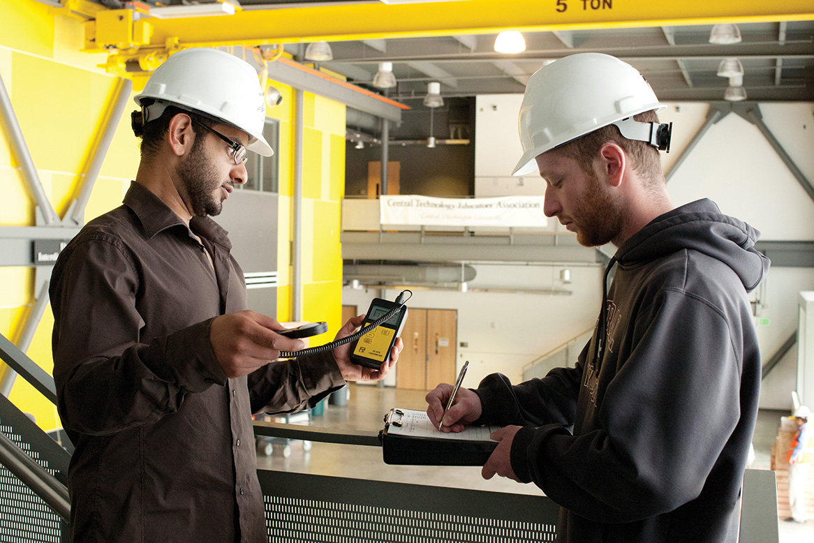 CMGT students look at an instrument in a lab