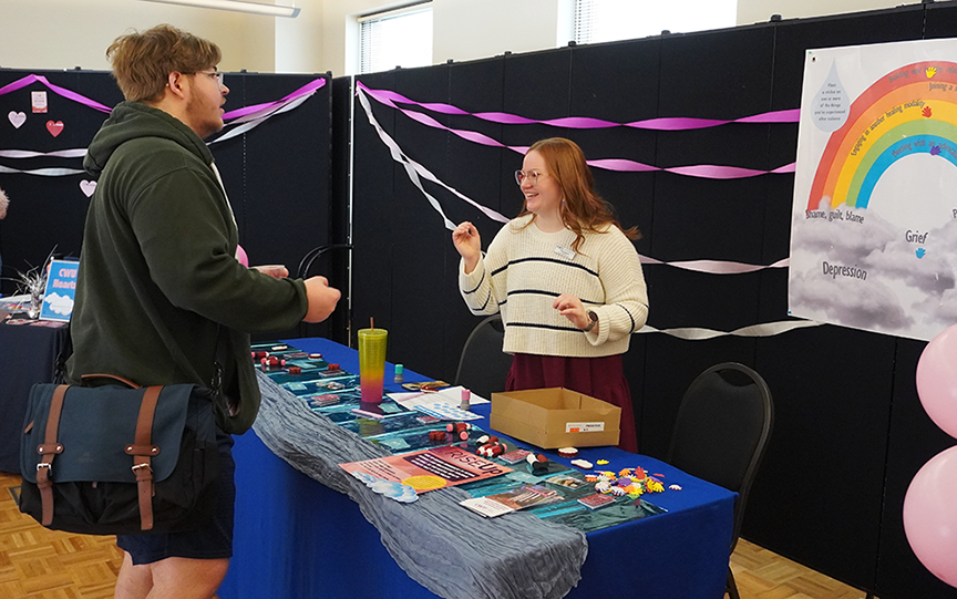 One of the booth representatives at Coping With Clouds interacts with a student.