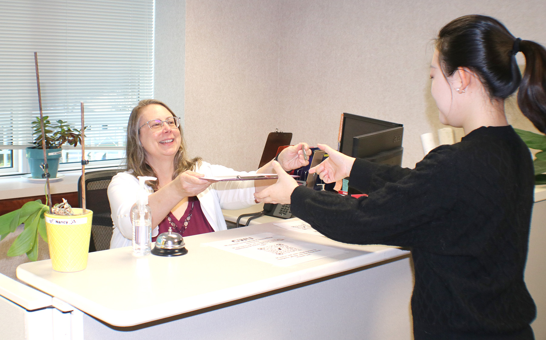 A front desk employee hands resources to a patient