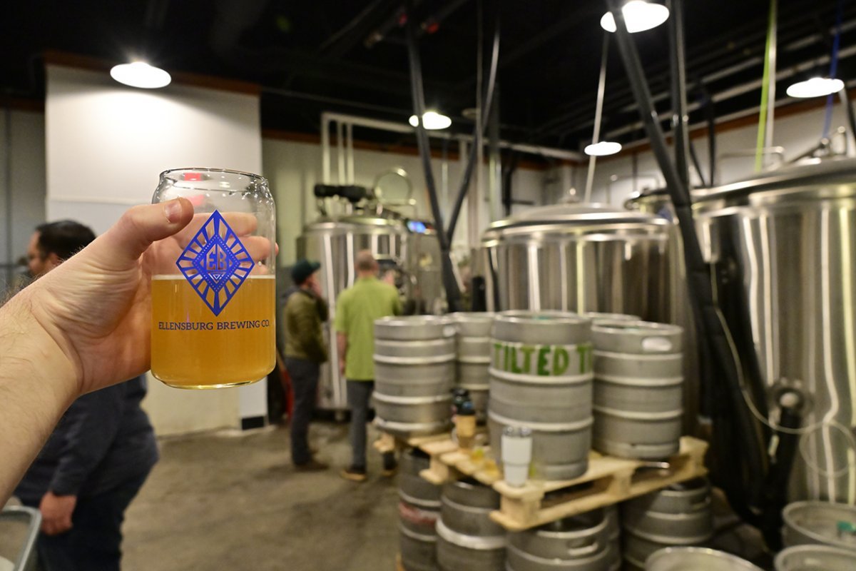 Holding up a pint in front of kegs at Ellensburg Brewing Co.