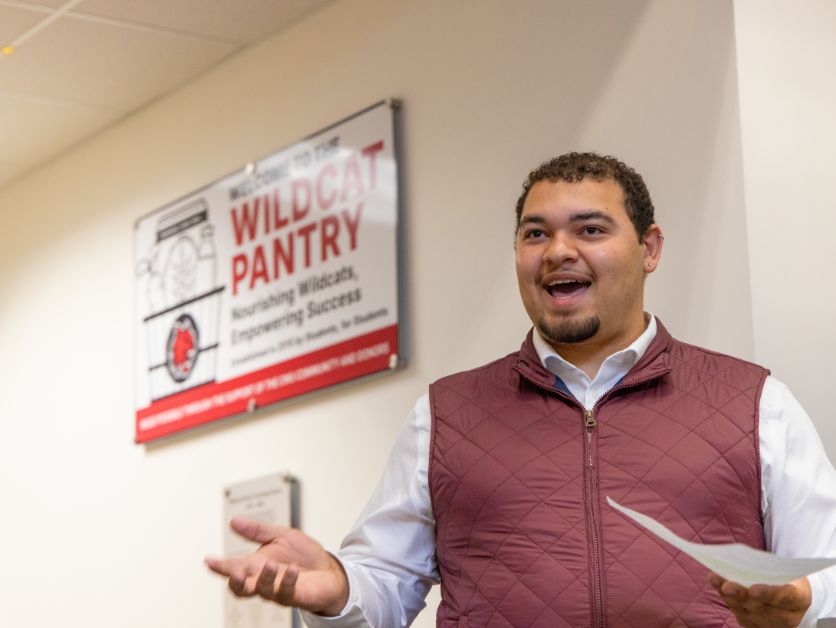 Photo of Charles Johnson in front of the Wildcat Pantry sign