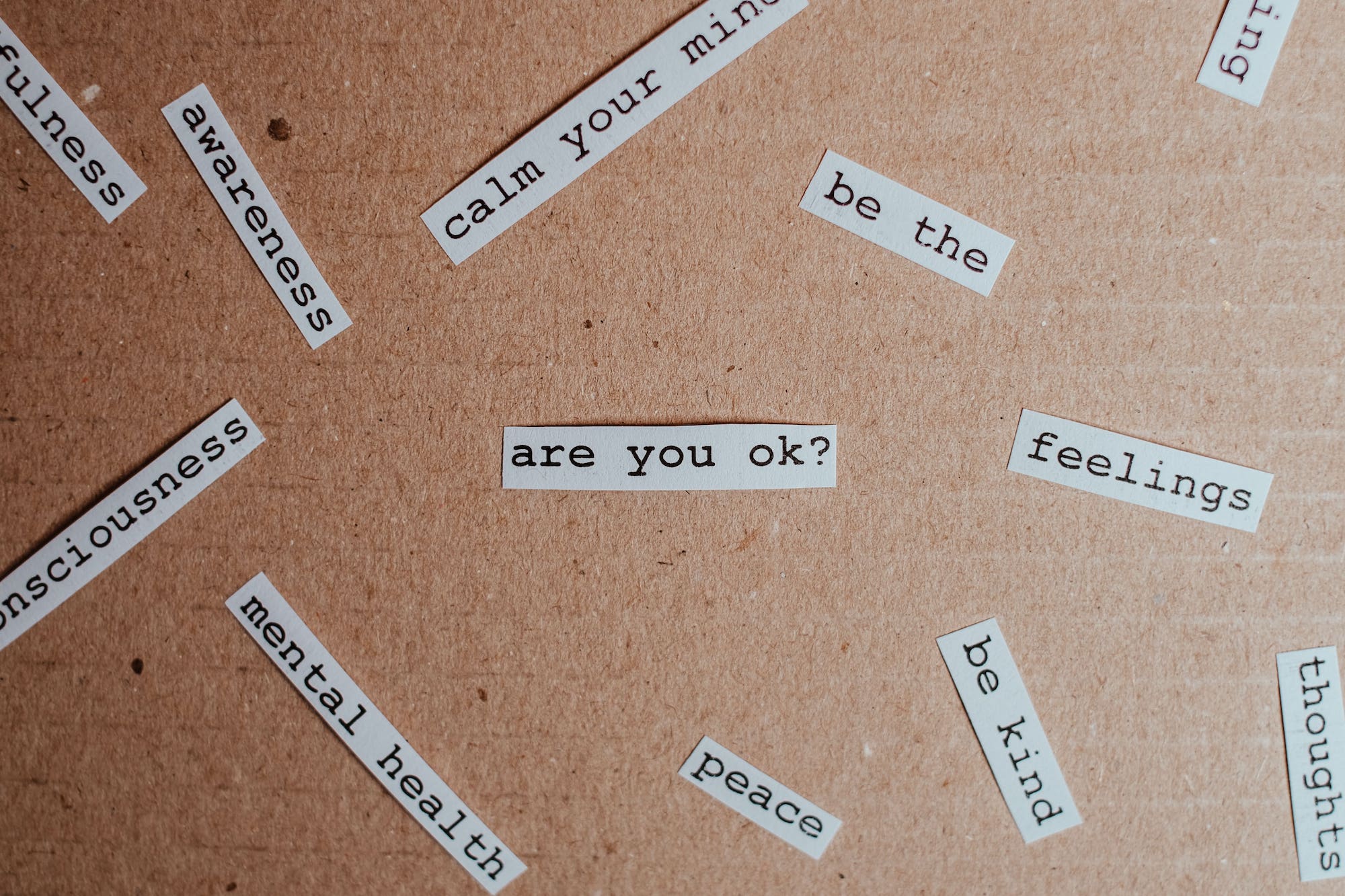 white text boxes on cardboard background featuring mental health related words