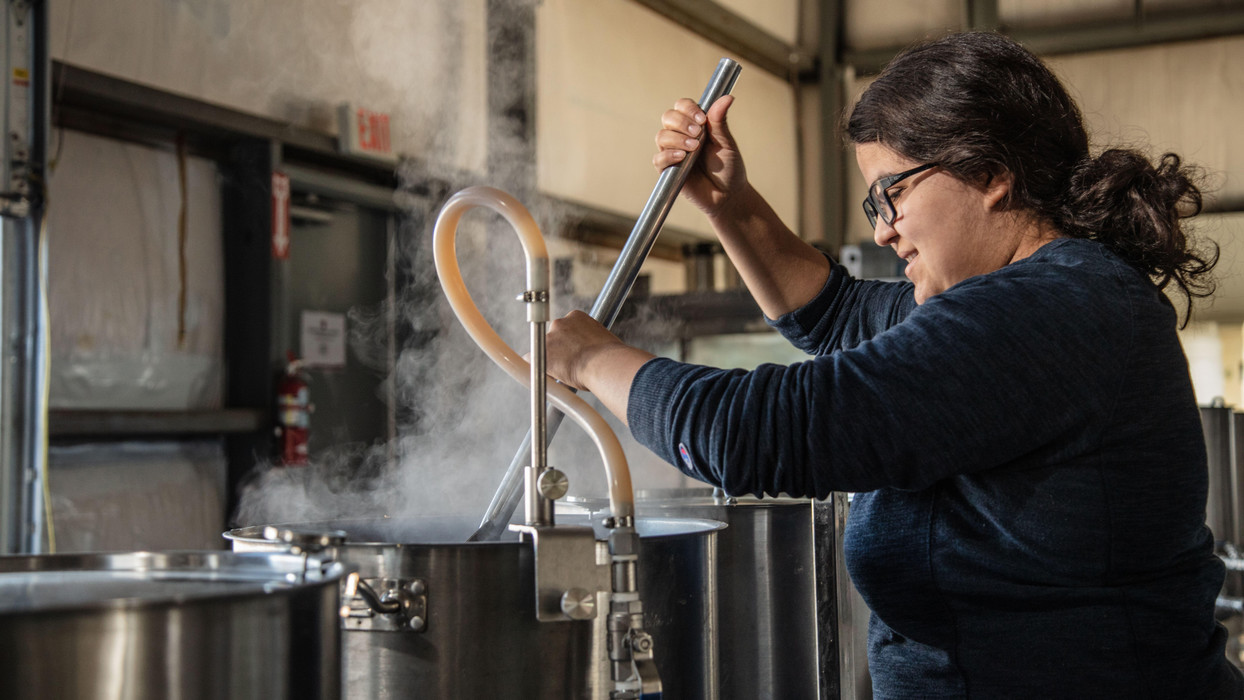 A student stirs a brew kettle