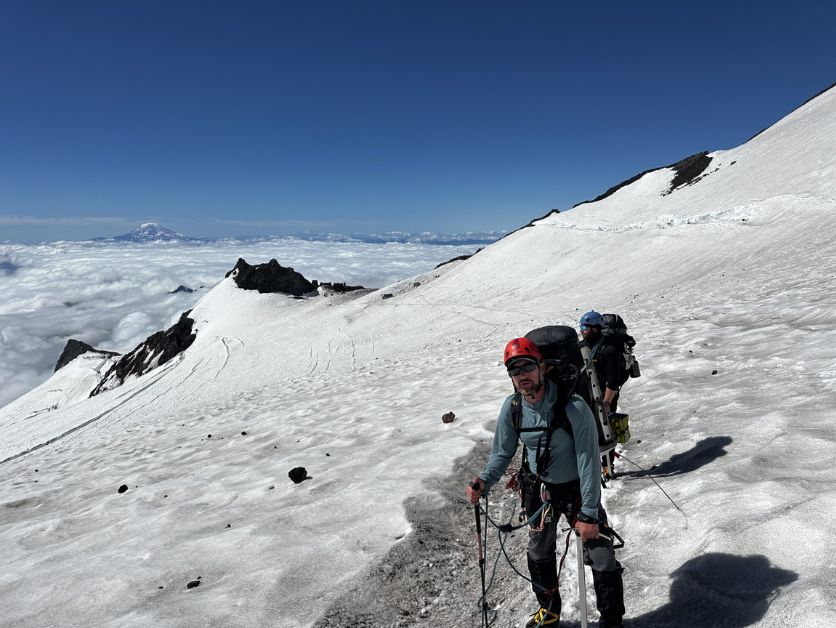 A CWU police officer scrambles through snow on his way up Mount Rainier