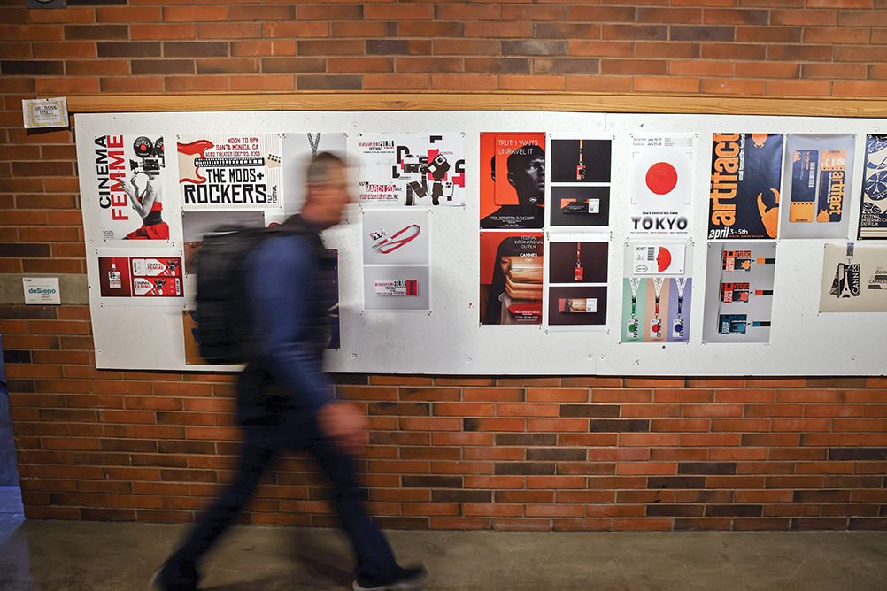 A student walks past the design wall in the CWU Graphic Design department