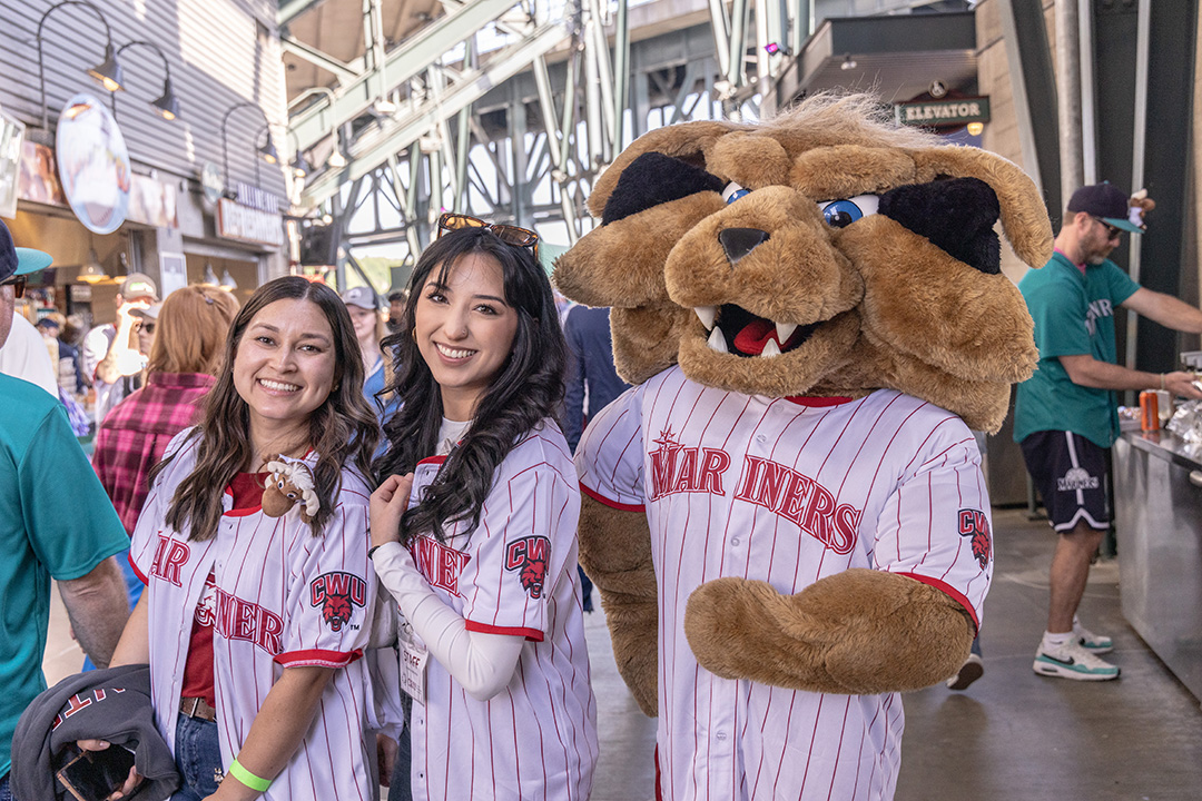 Two alums take a photo with Wellington at a recent CWU Night at the Mariners event