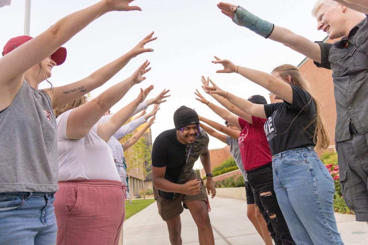 A student runs through a tunnel of classmates with their arms up