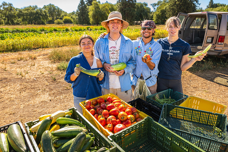 Student workers hold up produce at The Farm