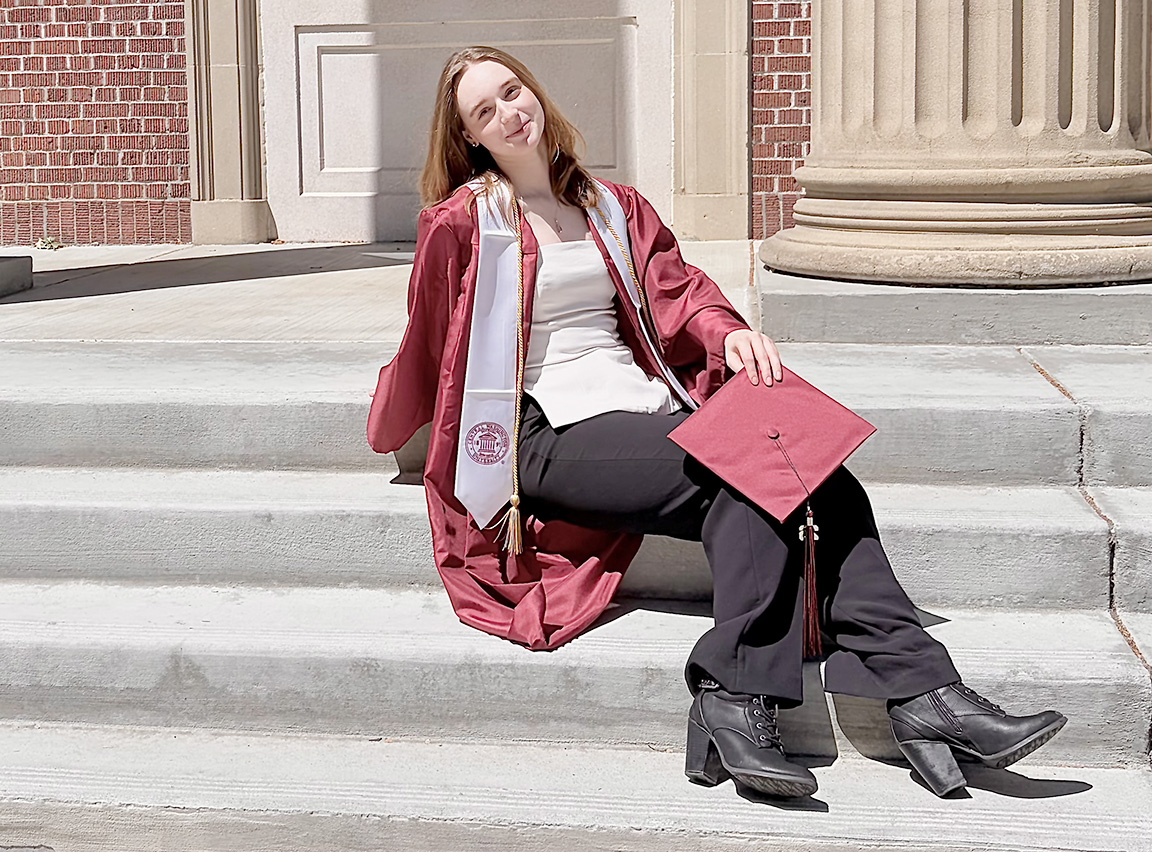 Kaelan Kavanaugh in her graduation attire outside Shaw Smyser Hall