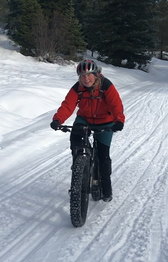 Kara Gabriel rides her bike down a snowy hill