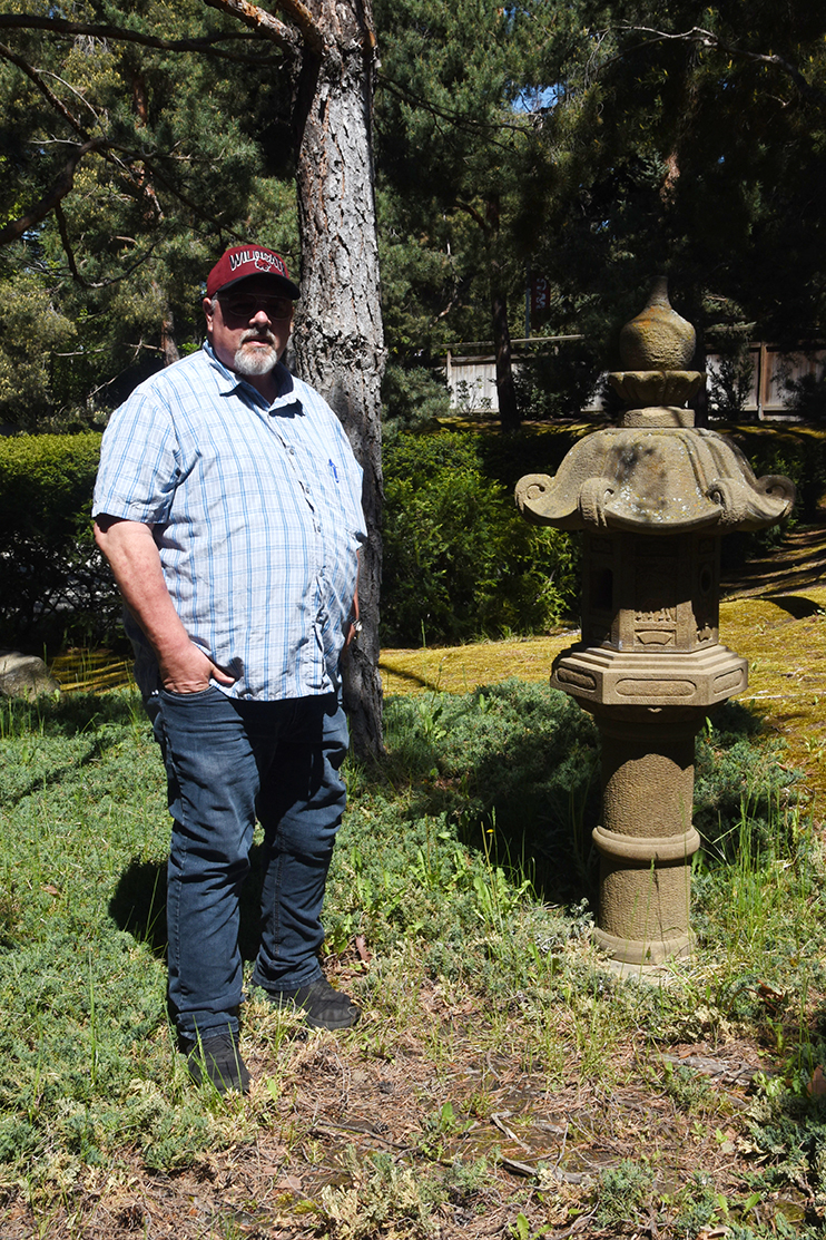 Keith Jones stands next to a statue in the Japanese Garden
