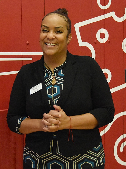 Monique Gonzales poses in front of the new CWU Dining Services wall 