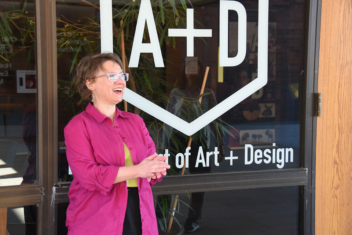 Rachel Kirk stands in front of the Art + Design decal in Randall Hall