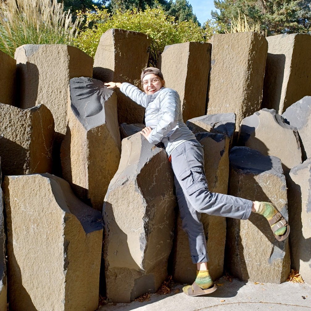 Raelynne Crow leans over to touch a stone sculpture 