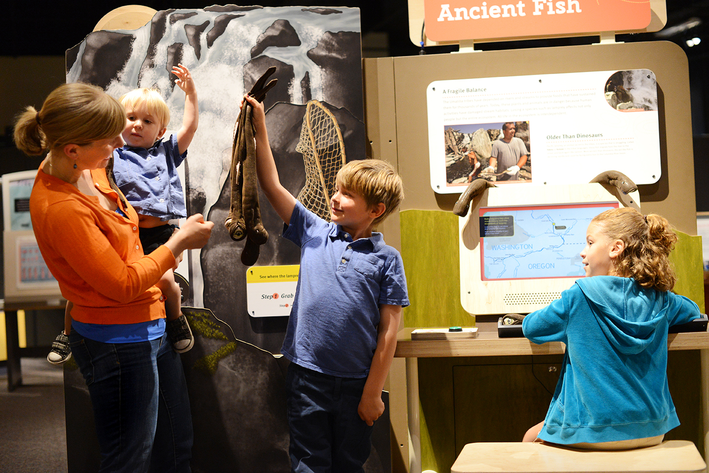 A mother and her children interact with the Roots of Wisdom exhibit