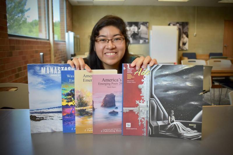 Ruby Nambo poses for a photo with some of the publications where her poetry has been published.