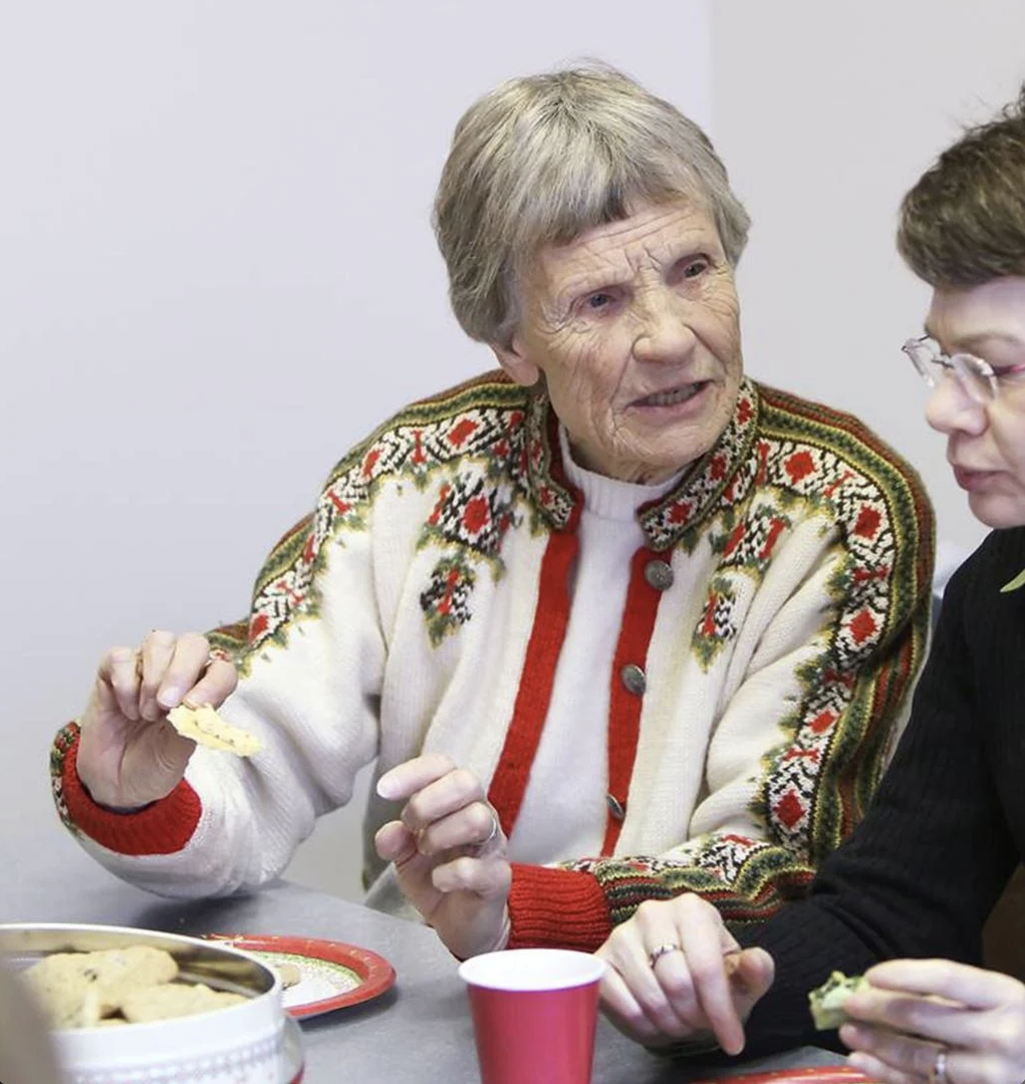 Ruth Harrington speaks to a friend while sitting at a lunch table
