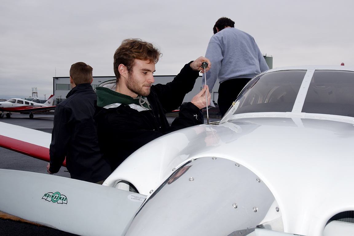 First-year Aviation student Eric Davis checks the oil on a CWU plane.