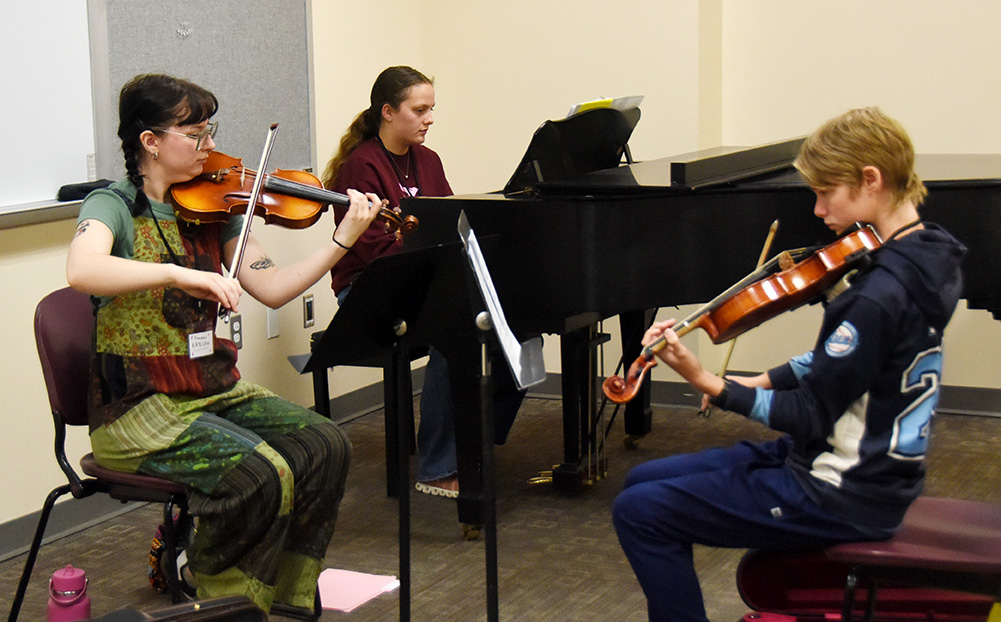 Two CWU student instructors engage in a chamber music session with a SLYM participant.