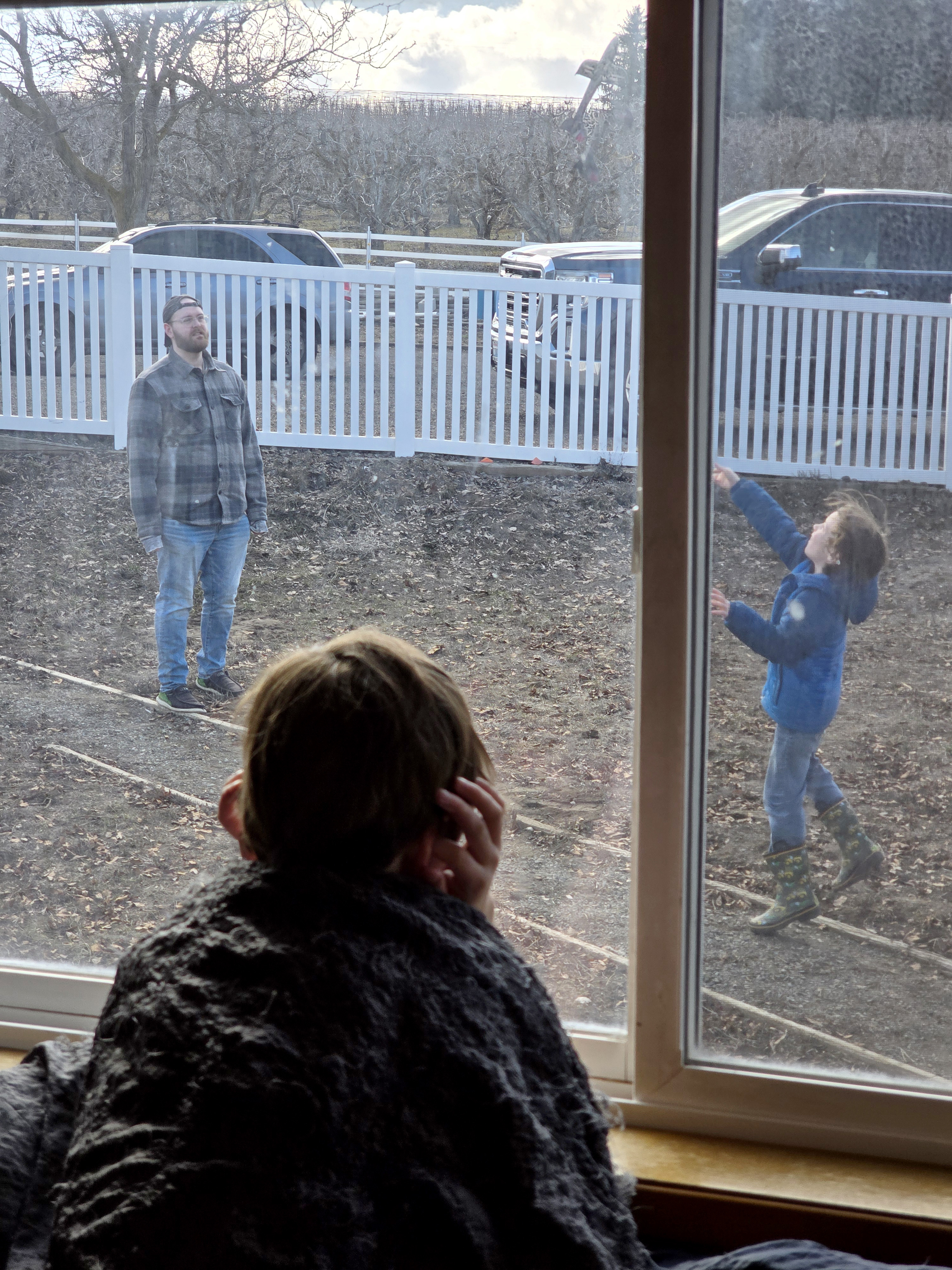 Ethan Berger works with one of the Lathrop boys outside while his brother watches through the window