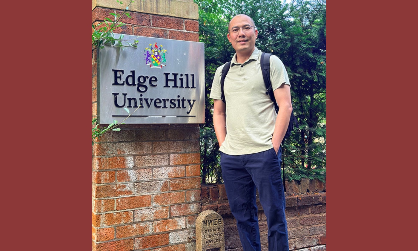 Professor Tanjian Liang next to the Edge Hill University sign.