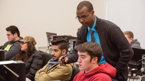 A CWU Education professor works with two students in the classroom