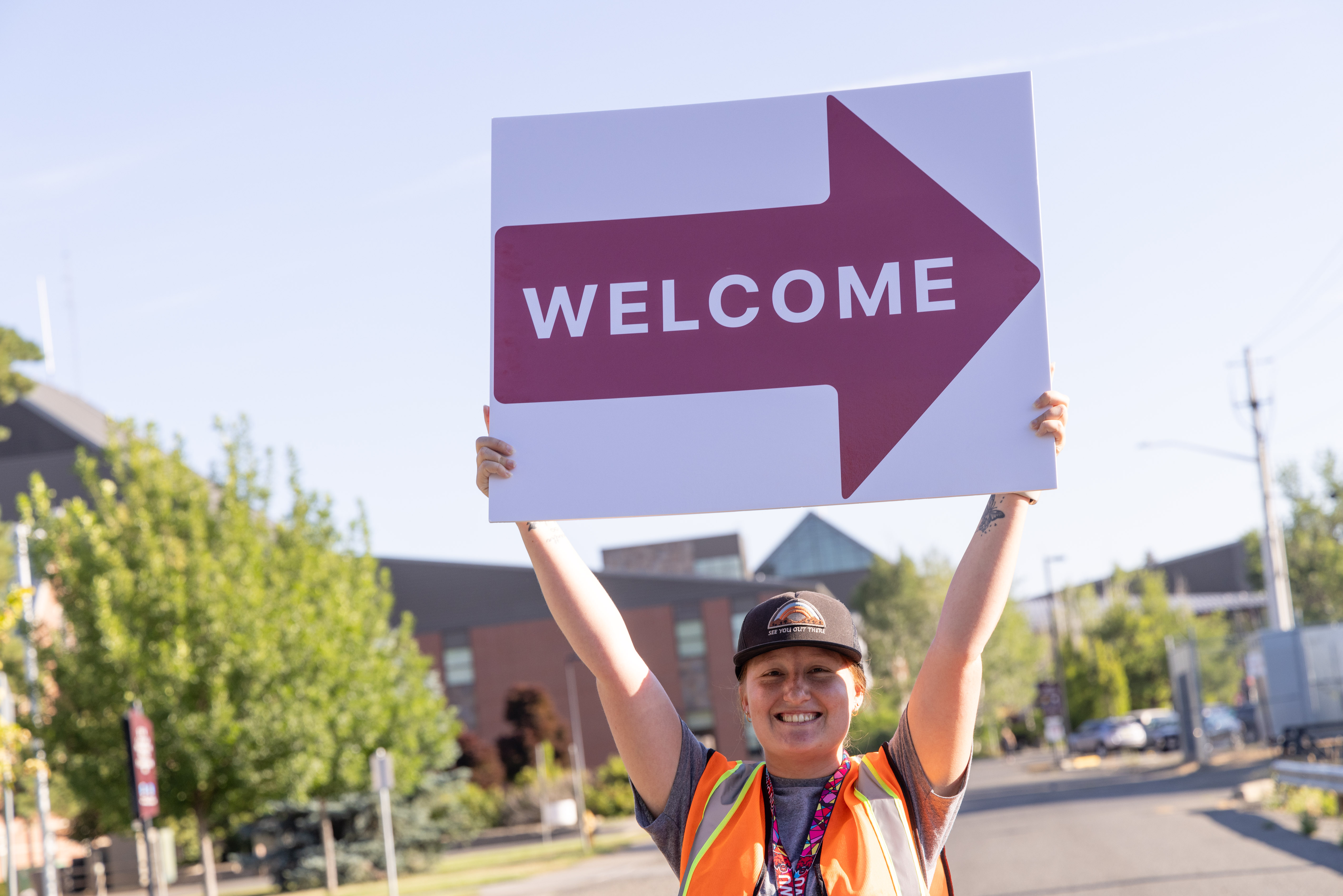 Orientation leader holding a welcome sign on the CWU campus.
