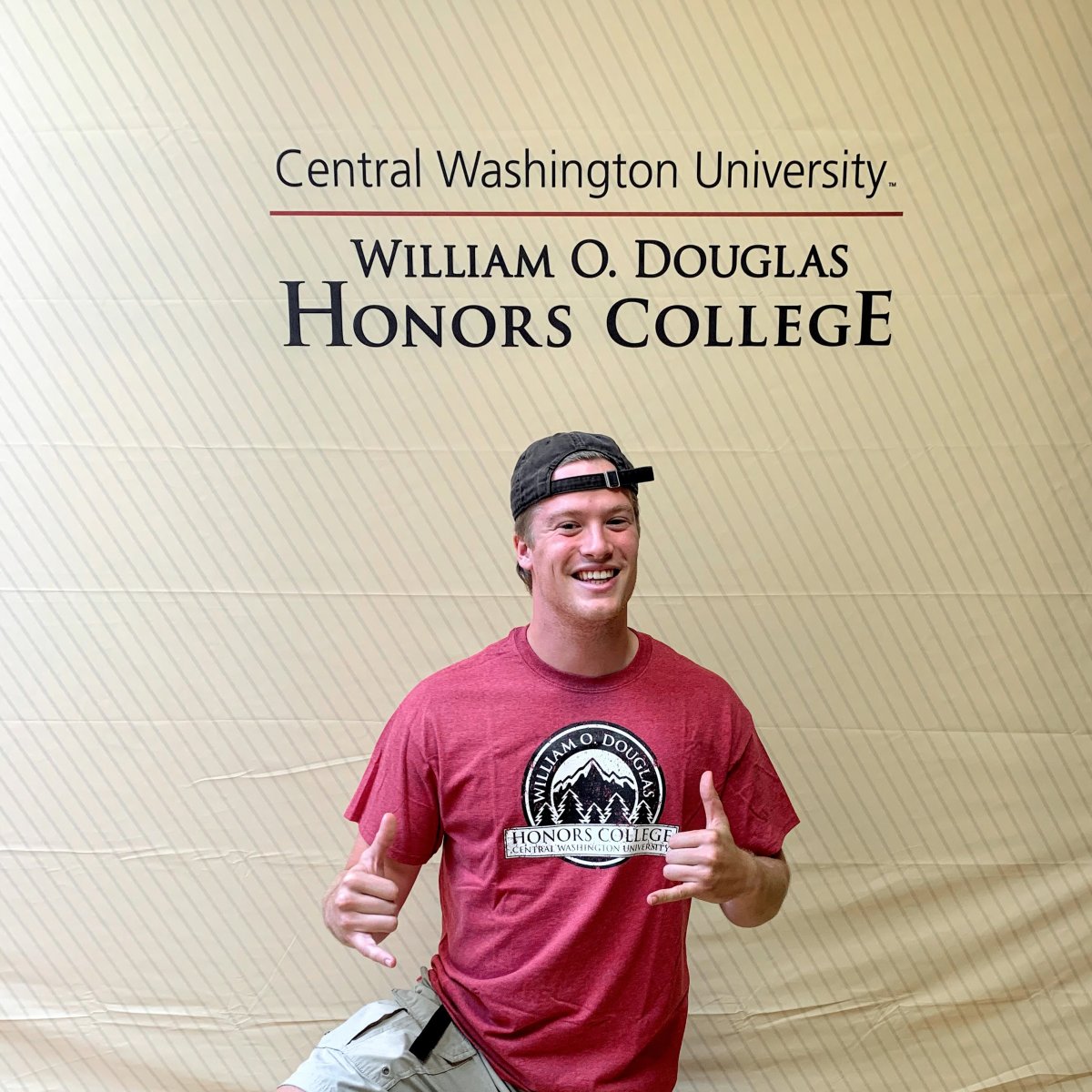 Noah Christy smiling posing in front of a CWU Douglas Honors College background.
