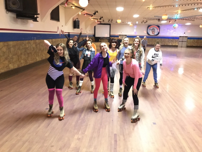 Club members roller skating at a roller rink during an 80's themed skate night