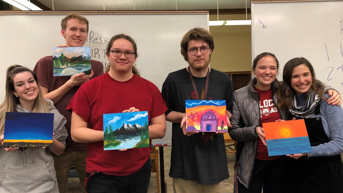 Six CWU Douglas Honors College students posing and holding up small art canvases.