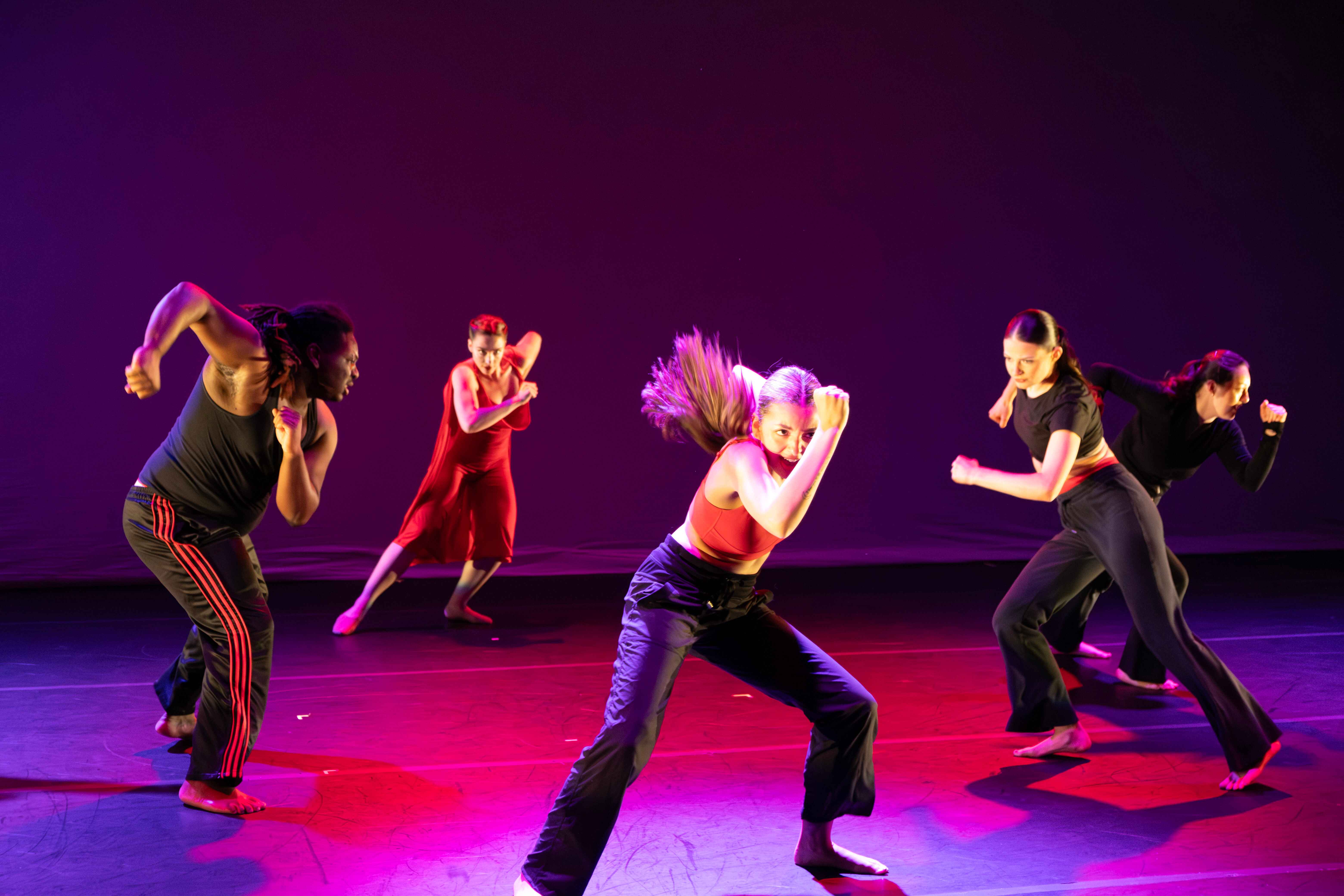 A group of five CWU students performing a dance with CWU's dance program under colored lights.