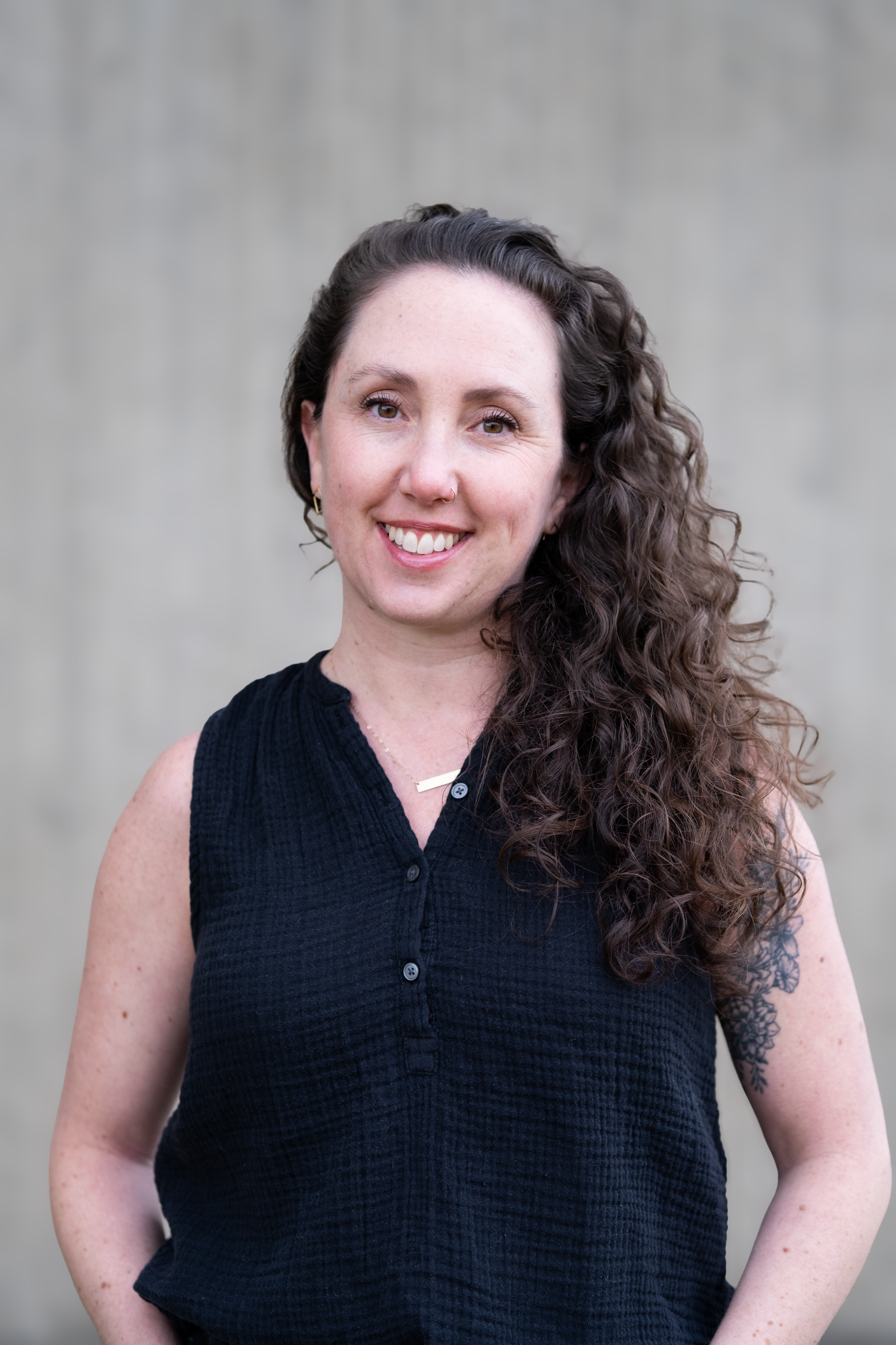 Woman with long curly hair wearing a sleeveless black top