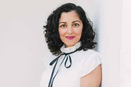 Portrait of Aimee Nezhukumatathil smiling at the camera in a white blouse with a thin black tie
