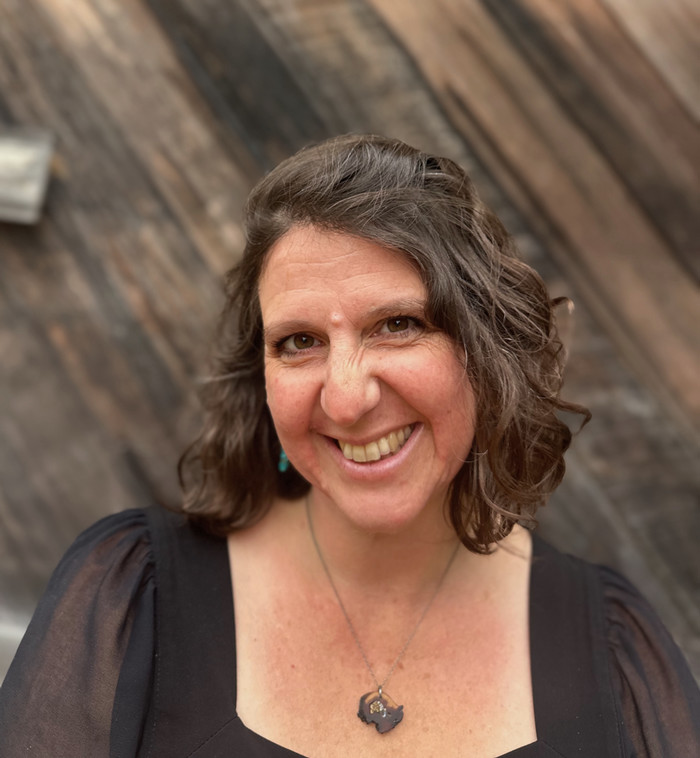 Author photo of Maya Jewell Zeller wearing black and smiling at the camera