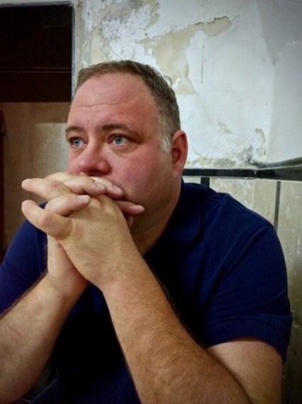 Knox Gardner sitting with hands folded in front of his face